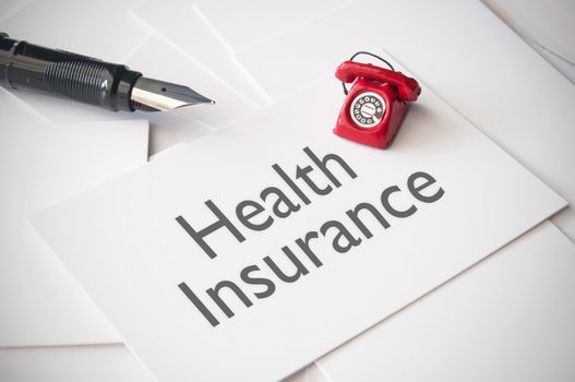 Small telephone on top of business card with health insurance