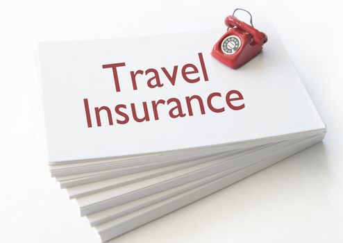 Small telephone on top of a stack of contact cards with travel insurance 