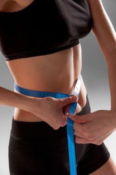 Fit and healthy waist measured with a tape isolated on gray