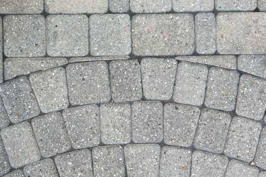 Circular inlaid pattern in grey brickwork on the floor of an exterior patio in a full frame architectural background viewed from above