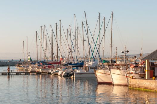CAPE TOWN, SOUTH AFRICA - DECEMBER 11, 2014:  Sunset at the harbor in Gordons Bay with building of The Strand in the background