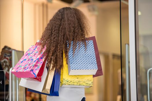 back view of  beautiful young woman with a shopping bags in the mall