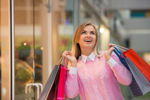 beautiful young woman goes shopping  with a fashion store window with manikin in the background.