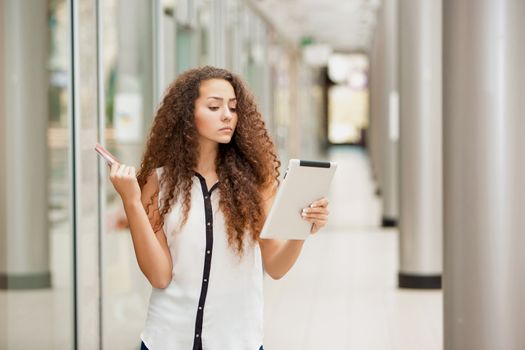 Beautiful young girl paying by credit card for shopping with a laptop against the background of the shopping center