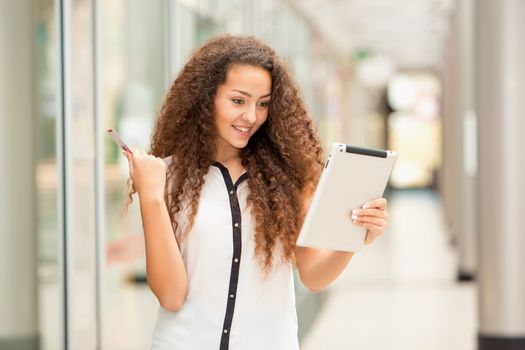 Beautiful young girl paying by credit card for shopping with a laptop against the background of the shopping center