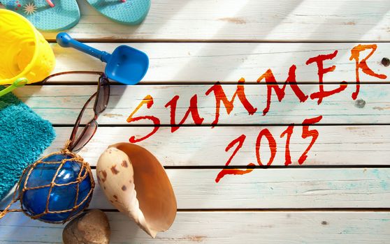 Summer vacation beach items including towel, sunglasses and bucket and spade over boards