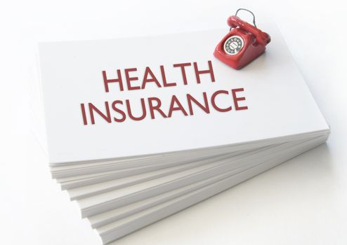 Small telephone on top of a stack of business cards with health insurance 