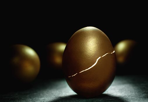 Gold nest egg hatching with light inside symbolising investments such as retirement and savings 