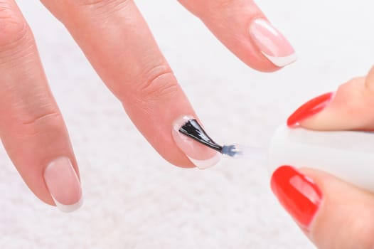 manicure applying, brushing fingernails with clear enamel