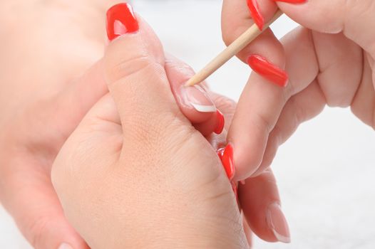 beauty salon, manicure applying, cleaning the cuticles with wooden stick