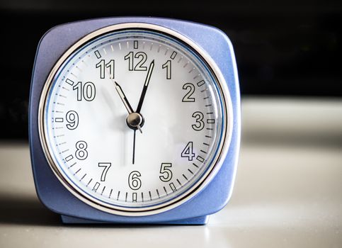 Old fashioned azure morning alarm clock, display eleven, over a bedroom forniture