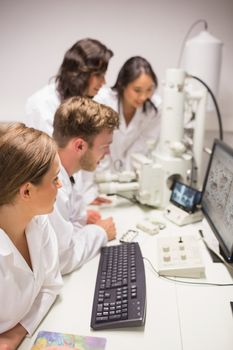 Biochemistry students using large microscope and computer at the university