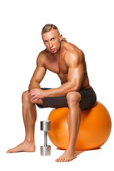 Shaped and healthy body man  sitting on fitness ball isolated on white background