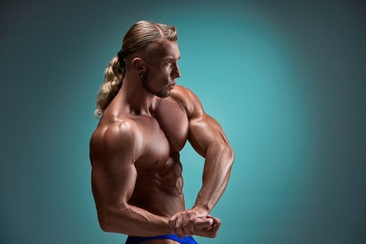 torso of attractive male body builder on blue background.