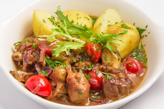 roast meat with potatoes and vegetables. potatoes, tomatoes, greens, lettuce, onions, meat, hearty. On white background