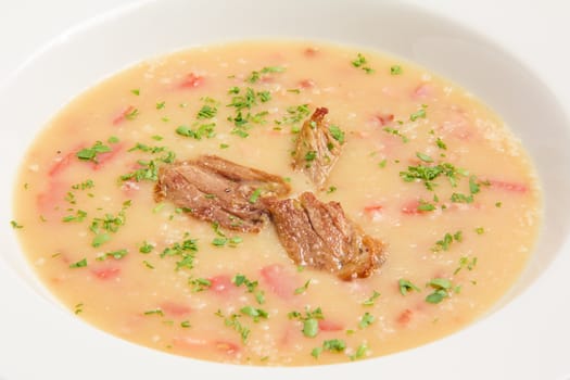 bean soup with potatoes, duck, bacon, tomatoes and parmesan cheese in a white plate