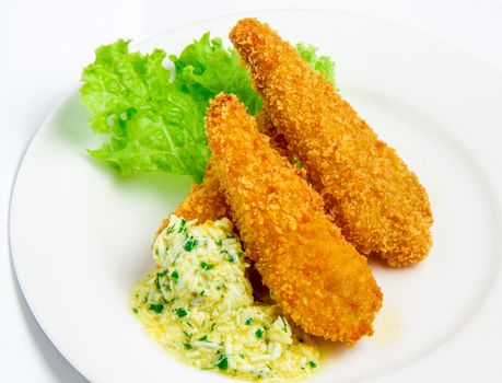 Breaded fish fillet with cream and egg sauce on a white plate