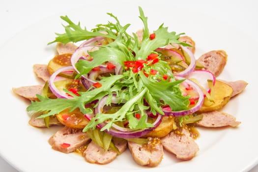 Bavarian salad with sausage, vegetables, potatoes, lettuce, onions, mustard. On white background