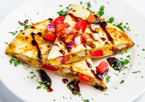 corn tortilla stuffed with chicken, cheese and vegetables on white plate