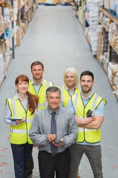 Team standing behind their boss in warehouse