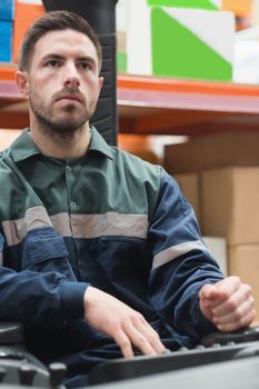 Portrait of focused driver operating forklift machine in warehouse