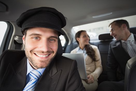 Handsome chauffeur smiling at camera in the car