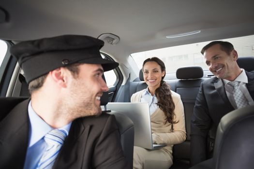 Handsome chauffeur smiling at clients in the car