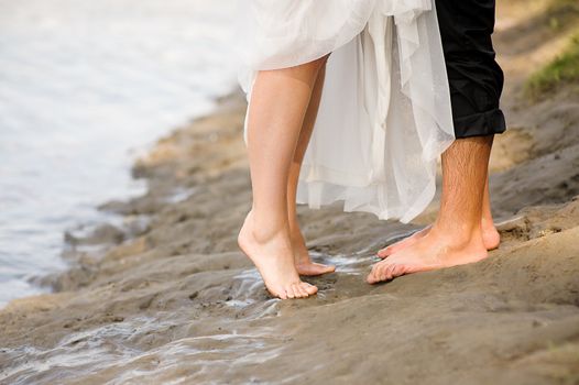 Loving young couple hugging, kissing on the beach at sunset