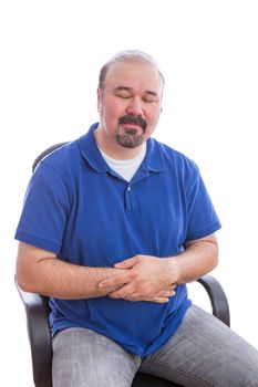 Close up Thoughtful Adult Man in Blue Polo Shirt, Sitting on a Chair with Eyes Closed and Holding his Stomach, Emphasizing Acceptance. Isolated on White Background.
