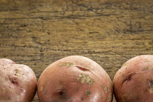 a row of three red potatoes on rustic wood with a copy space