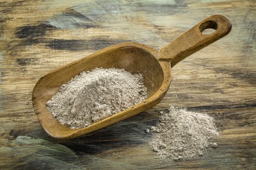 scoop and heap of gluten free buckwheat flour against painted wooden cutting board