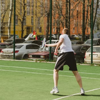 young man play tennis outdoor on tennis field at early morning