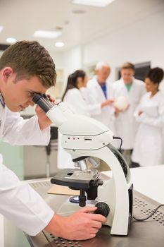 Young medical student working with microscope at the university