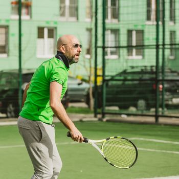 young man play tennis outdoor on tennis field at early morning