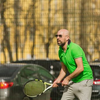 young man play tennis outdoor on tennis field at early morning