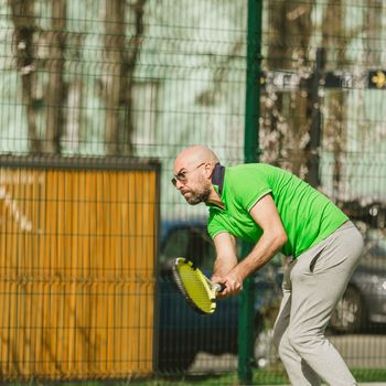 young man play tennis outdoor on tennis field at early morning