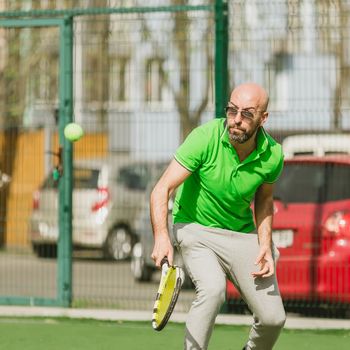 young man play tennis outdoor on tennis field at early morning