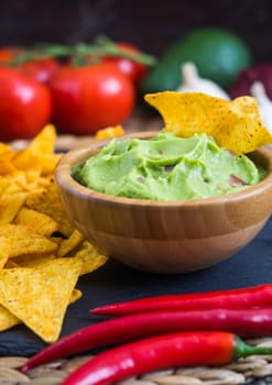 Guacamole in Wooden Bowl with Tortilla Chips and Ingredients