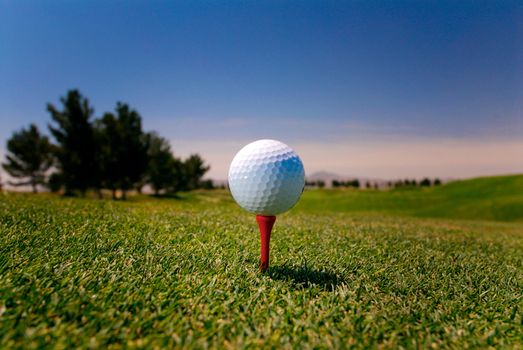 Image of a golfball on a red tee on golf course