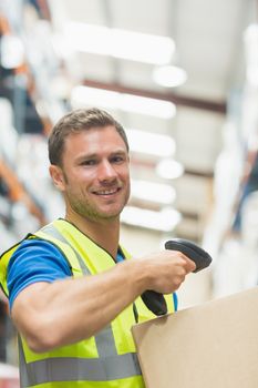 Smiling manual worker scanning package in warehouse