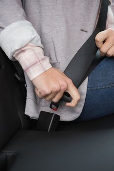 Woman putting on her seat belt in her car