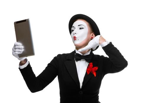 business woman in the image mime holding tablet PC and  looking at a laptop as a mirror  isolated on white background. concept of concept of narcissism at work