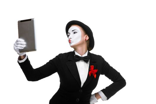 business woman in the image mime holding tablet PC and  looking at a laptop as a mirror  isolated on white background. concept of concept of narcissism at work