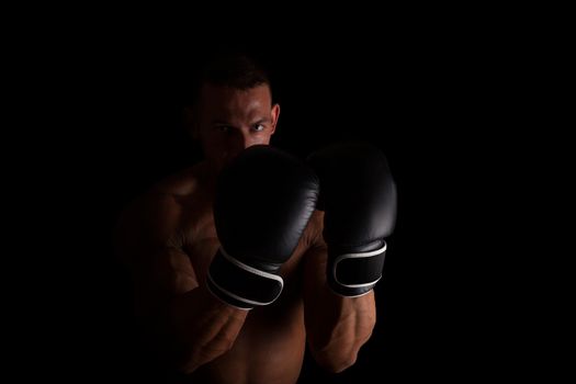 Boxer. Young sexy muscular shirtless man with boxing gloves looking into camera isolated on black background. Sport and fitness.  