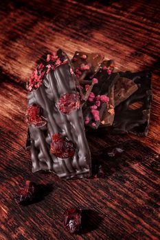 Culinary gourmet chocolate pieces on dark wooden background. Luxurious dark chocolate.