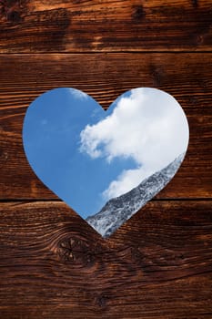 Wooden background with heart shape window with Austrian Alps in it. Traditional Austria.