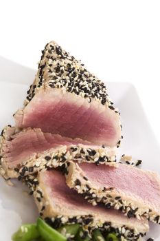 Tuna slices with white and black sesame seeds and lemon slices on white plate. Culinary seafood, healthy eating.