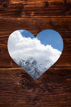 Austrian Alps in heart shape window on vintage wooden background. Snow covered mountain. Winter.