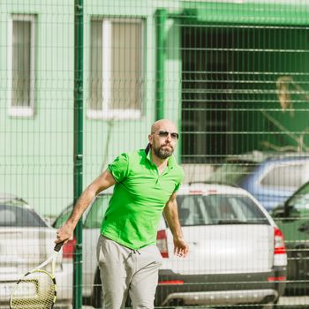 young man play tennis outdoor on tennis field at early morning