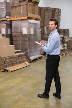 Warehouse manager looking at camera in a large warehouse